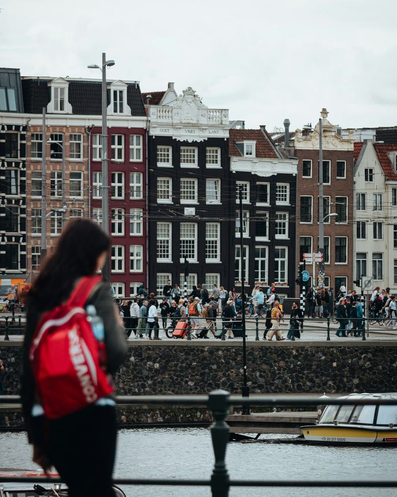 Une personne vue de dos regarde un canal et des immeubles à Amsterdam