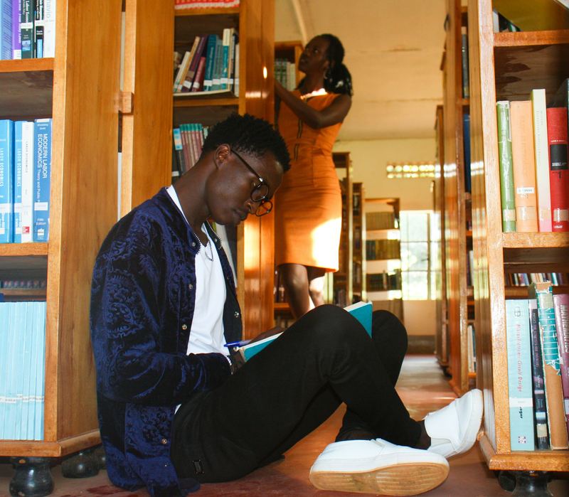 Une personne lit un livre entre les rayonnages d’une bibliothèque